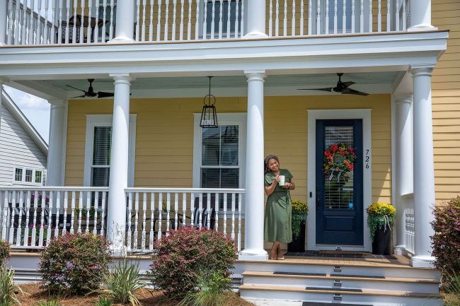 Woman leaning on column atop steps to her porch