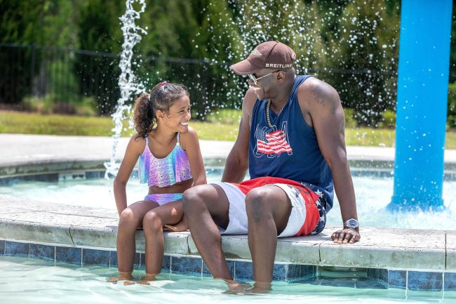 A father and daughter with feet in a pool