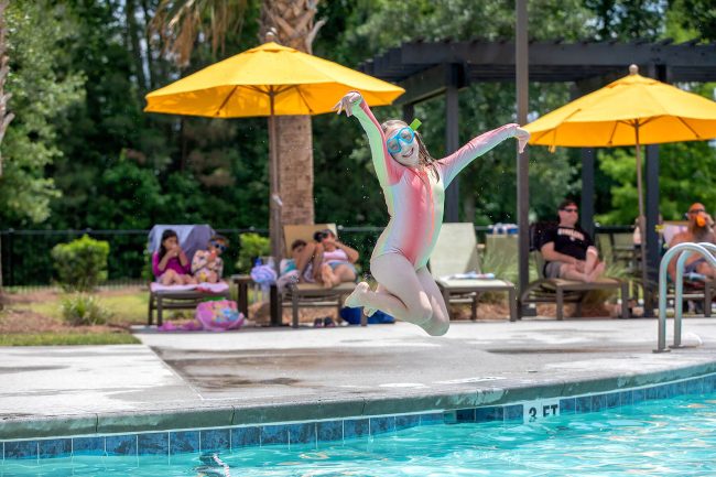 Young girl with swimming mask posing as she jumps into a pool